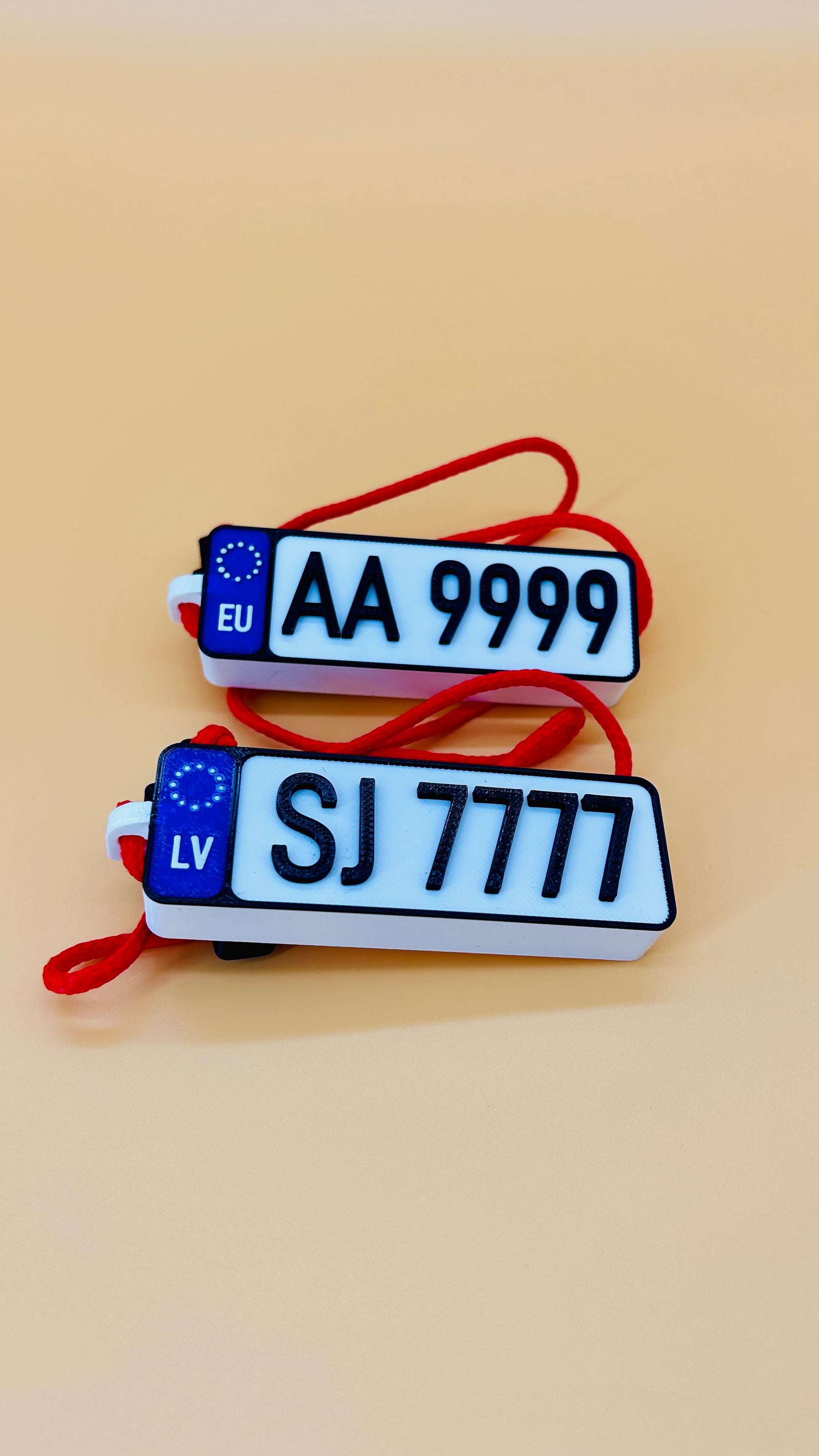 Two license plate-shaped keychains with text on a beige background