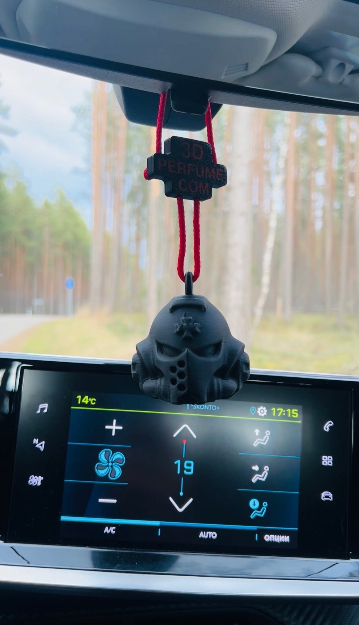 Car dashboard with a skull-shaped air freshener hanging from the rearview mirror, displaying temperature and time.
