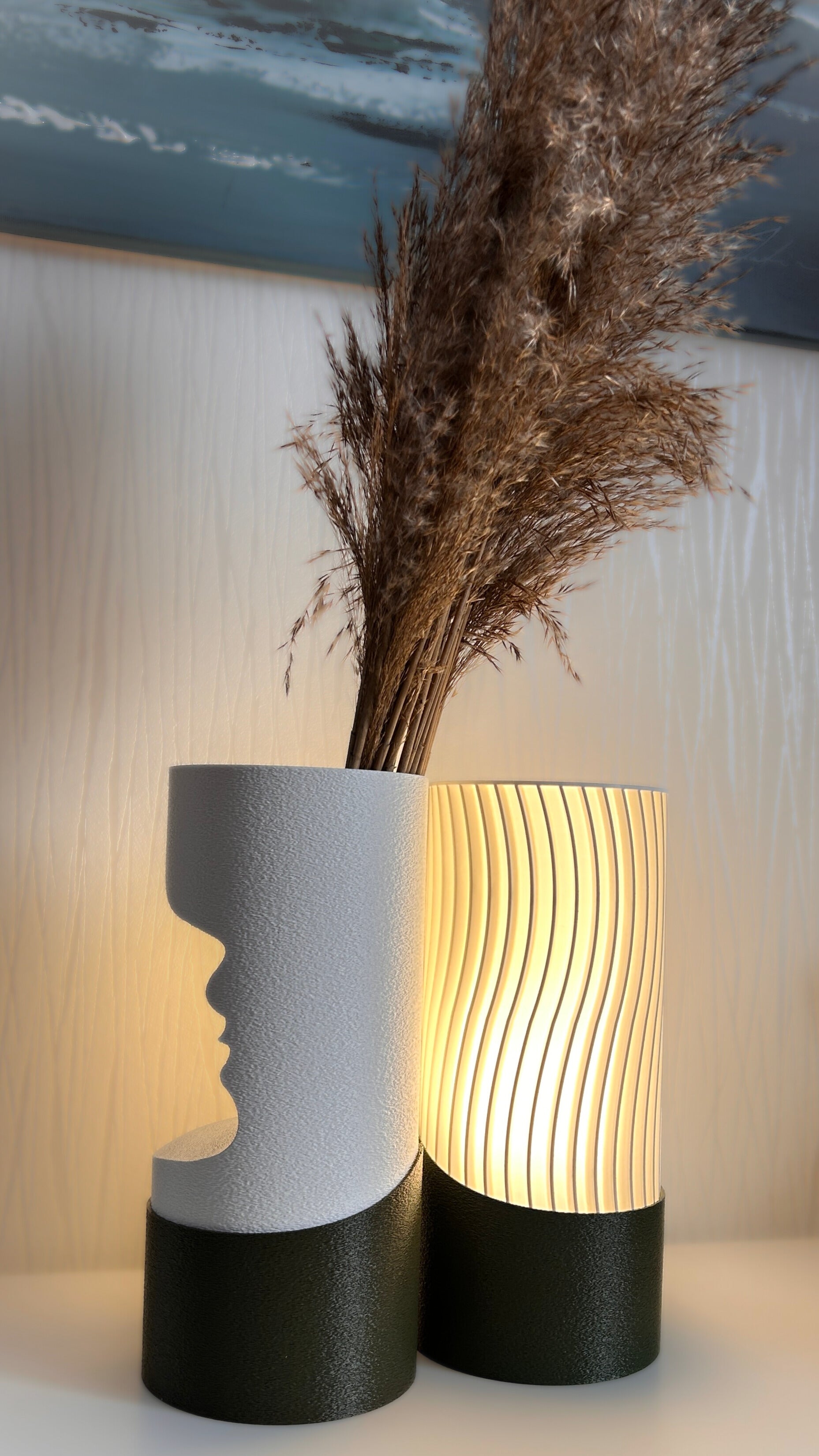 Two decorative vases with one featuring a face silhouette and the other with wavy design, on a light background.